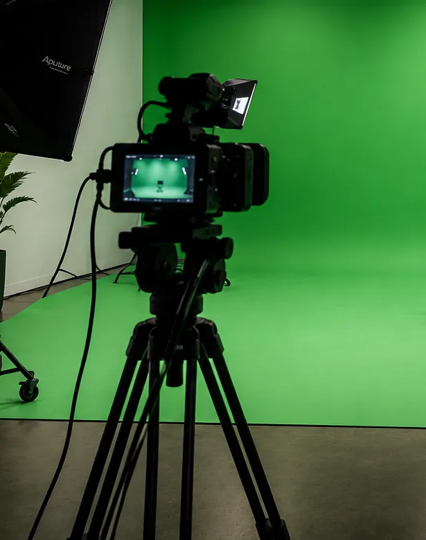Cinema camera on a tripod framed on the Reel Deal Studios green screen stage
