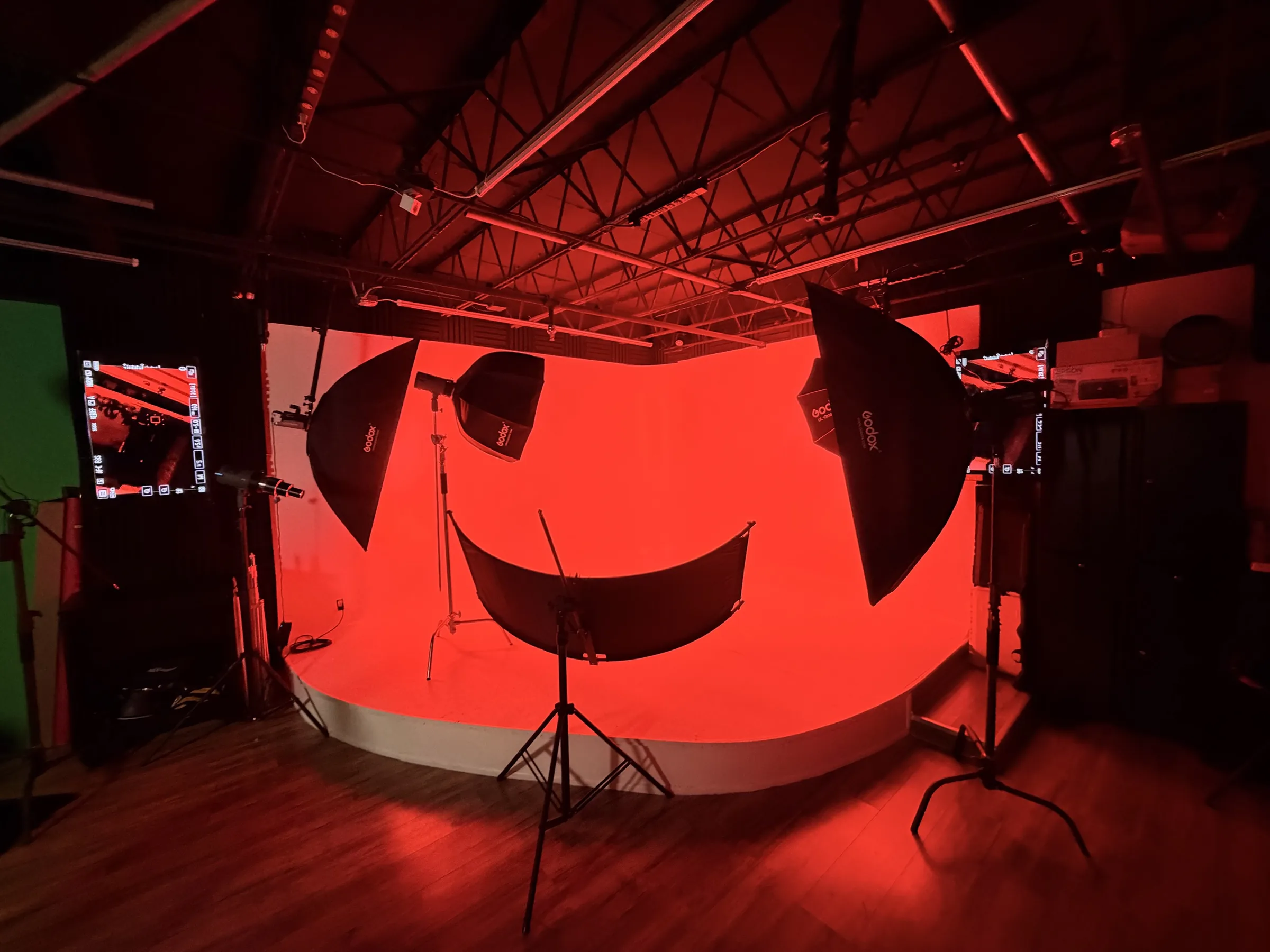 The cyclorama at Reel Deal Studios in Miami lit red, with softboxes, a reflector and light stands rigged in front of it